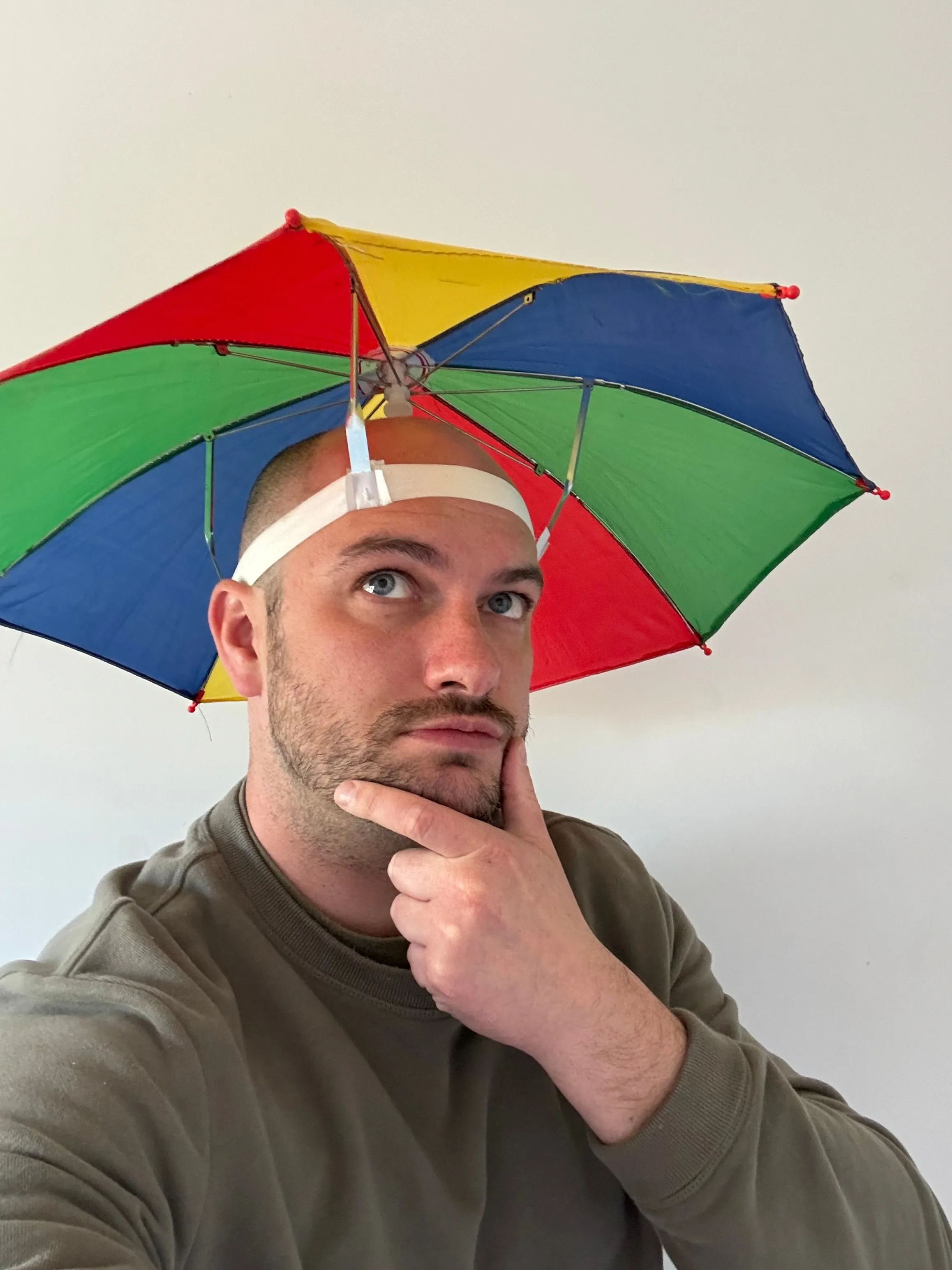 Andy Chadwick wearing a colourful umbrella hat, looking thoughtful